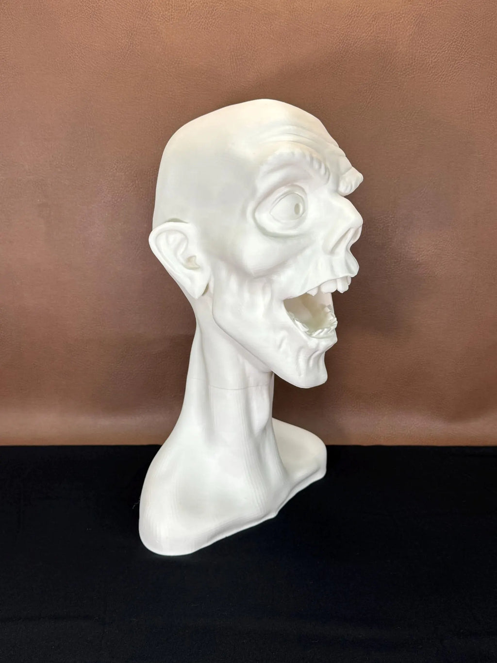 White 3D printed bust of a face winking with a dark brown background
