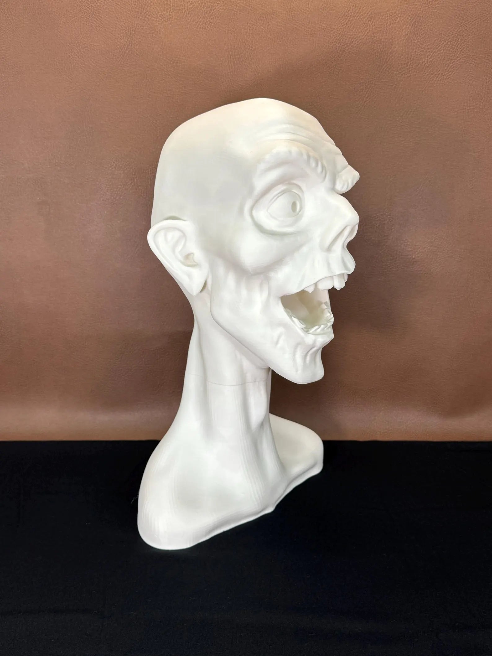 White 3D printed bust of a face winking with a dark brown background