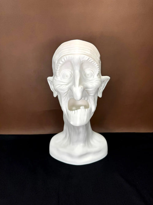 White 3D printed head sculpture with exaggerated features on a brown background
