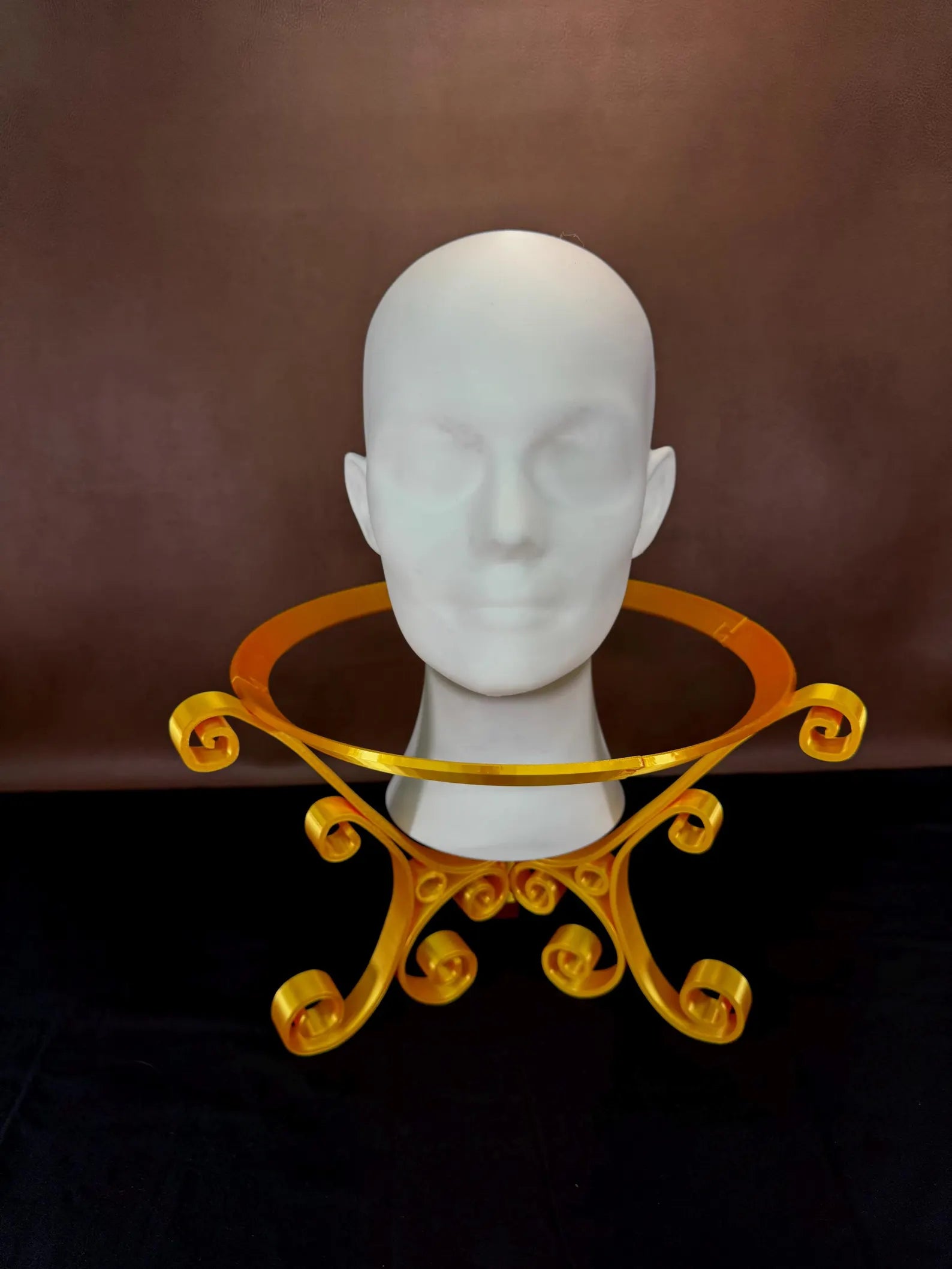 White 3D Printed head with a gold decorative ring stand on a brown background