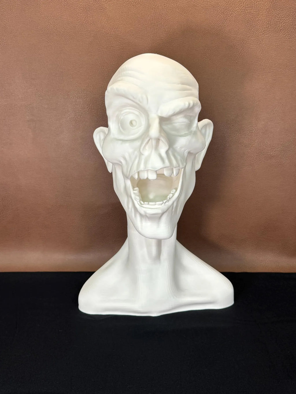 White 3D printed bust of a face winking with a dark brown background