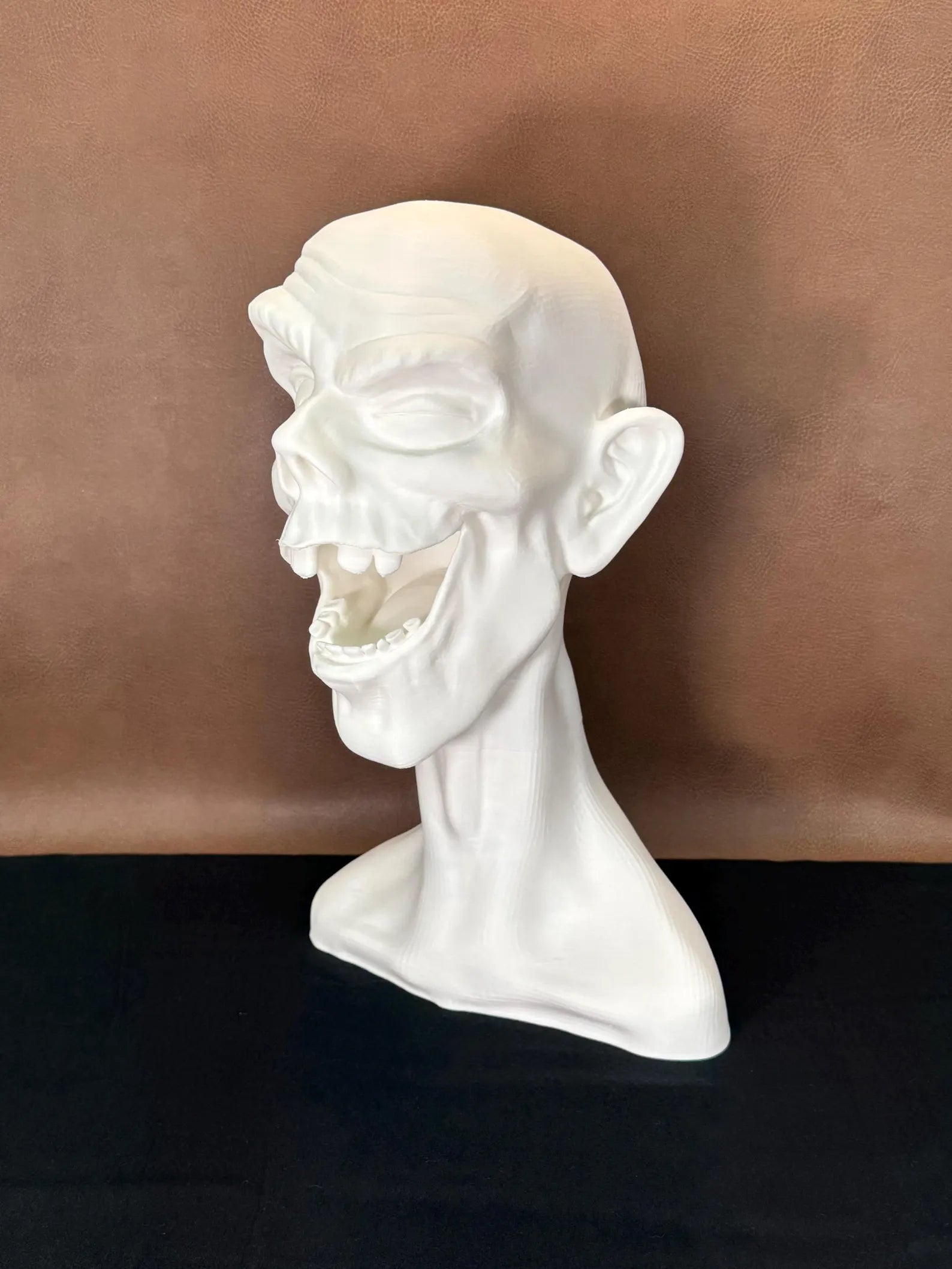 White 3D printed bust of a face winking with a dark brown background