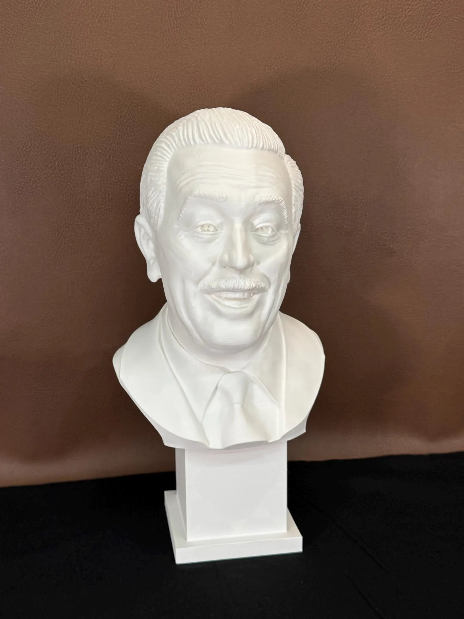 White 3D printed bust of Walt Disney on a brown background