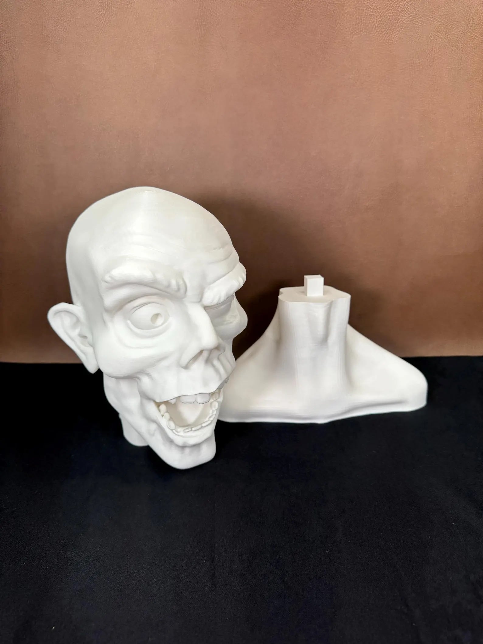 White 3D printed bust of a face winking in 2 pieces with a dark brown background
